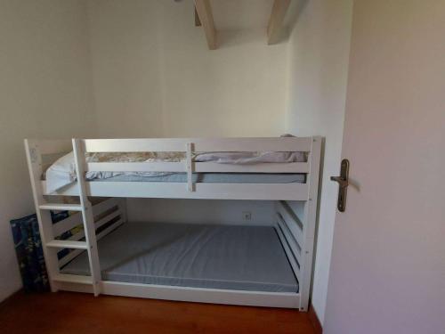 Cette chambre comprend un petit lit superposé blanc. dans l'établissement Maison climatisée avec jardin, terrasse et piscine, proche des campings - Marseillan - FR-1-326-693, à Marseillan