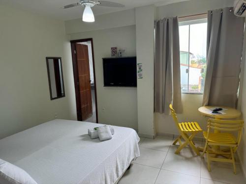 a bedroom with a bed and a table and a window at Hotel Aconchego Da Vila in Saquarema