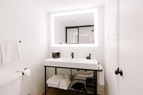 a white bathroom with a sink and a mirror at SeaLoft Oceanfront Hotel in Ocean City