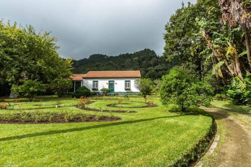 un jardin avec une maison blanche en arrière-plan dans l'établissement Casa das Duas Ribeiras, à Furnas