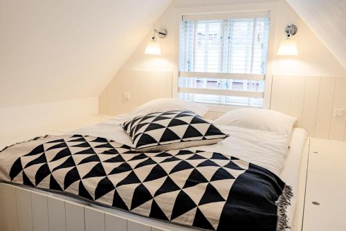 uma cama branca com almofadas pretas e brancas em Der kleine Carl em Wyk auf Föhr