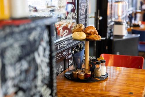 a table with a tray of pastries and bread on it at Backstage Hotel Amsterdam in Amsterdam