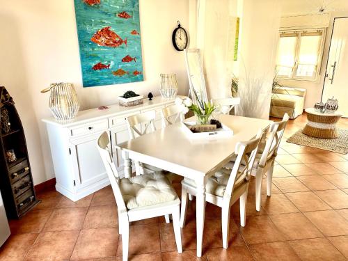 uma sala de jantar com uma mesa branca e cadeiras em Casa Sunshine 2.0 - Vacanze al mare em Punta Braccetto