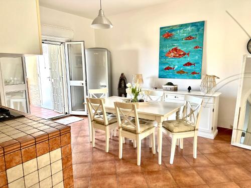 uma cozinha e sala de jantar com uma mesa branca e cadeiras em Casa Sunshine 2.0 - Vacanze al mare em Punta Braccetto