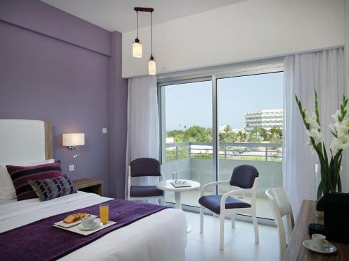 een hotelkamer met een bed en een tafel en stoelen bij Atlantica Sea Breeze, Adults Only in Protaras