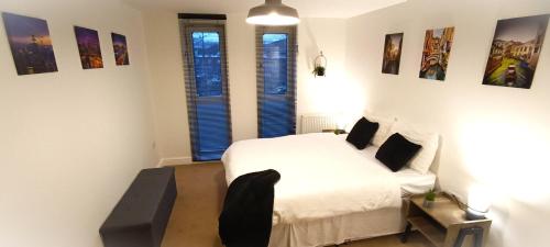 a bedroom with a white bed and two windows at 2 Bed Crawley Apt - Near Gatwick in Crawley