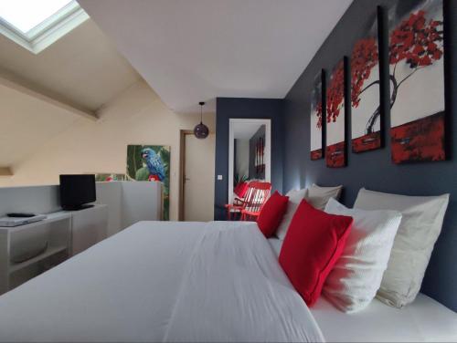 una camera da letto con un letto bianco con cuscini rossi di LE DUPLEX DU MARCHÉ a Châteauroux