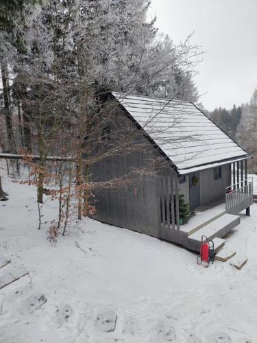 a small building with snow on the ground in front at Slow Huts in Miedzygorze