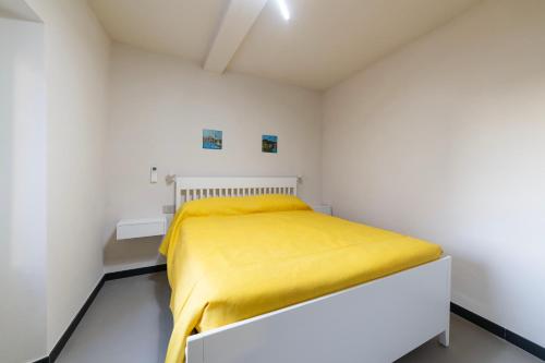 a bedroom with a bed with a yellow blanket at Mirabel Apartments Moneglia - Cinque Terre in Moneglia