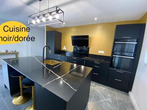 une cuisine équipée d'un comptoir noir et d'appareils électroménagers dans l'établissement Maison de charme en bord de mer avec jacuzzi, à Merville-Franceville-Plage