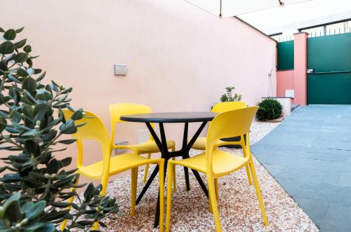 a table and four yellow chairs in a courtyard at Mirabel Apartments Moneglia - Cinque Terre in Moneglia