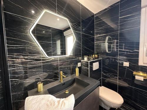 une salle de bain noire avec un lavabo et un miroir dans l'établissement Maison de charme en bord de mer avec jacuzzi, à Merville-Franceville-Plage