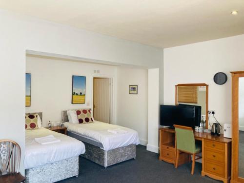 um quarto de hotel com duas camas e uma secretária em The Coach and Horses em Winchester