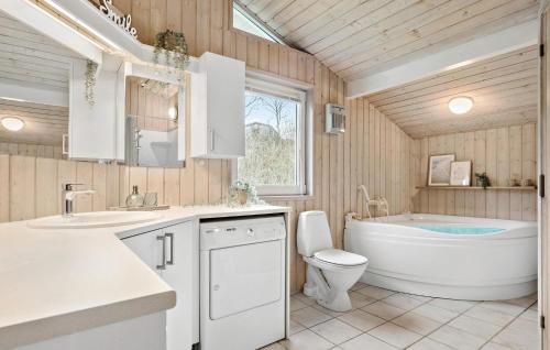 a bathroom with a tub and a toilet and a sink at Cozy Home In Ebeltoft With Sauna in Ebeltoft