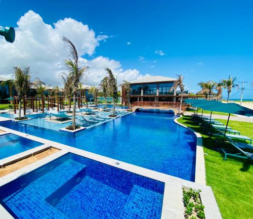 uma piscina num resort com palmeiras e cadeiras em Refúgio em Condomínio- Flecheiras em Trairi