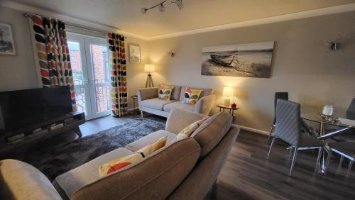 a living room with a couch and a tv at Peaceful Waterfront Apartment, Private Parking, Hull Marina in Hull