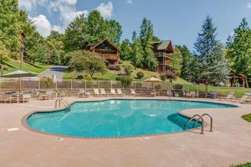 a large swimming pool with chairs and a house at Near Dollywood with Pool Table-Hot Tub-Fire Pit-Game Room in Pigeon Forge