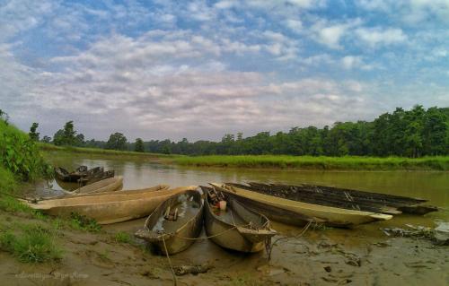 three boats sitting on the shore of a river at Hotel Horizon Homes - Sauraha Chitwan in Sauraha