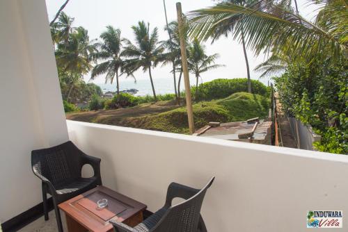 a balcony with chairs and a table and palm trees at Induwara Villa in Ahungalla