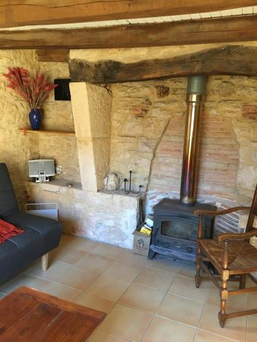 ein Wohnzimmer mit einer Steinmauer und einem Holzofen in der Unterkunft Le Pas de la Lande in Groléjac