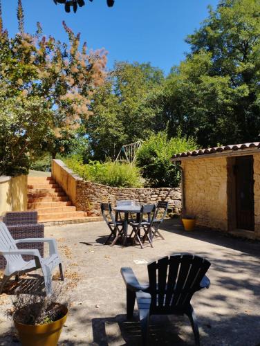 eine Terrasse mit einem Tisch und Stühlen sowie ein Steingebäude in der Unterkunft Le Pas de la Lande in Groléjac