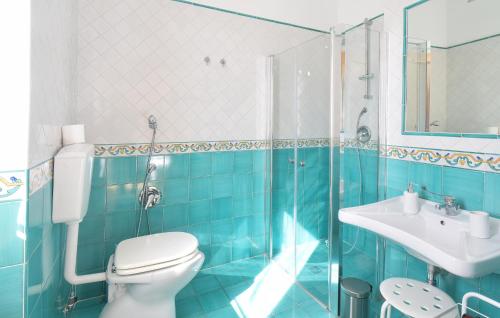 a blue tiled bathroom with a toilet and a sink at 3 Bedroom Stunning Home In Mondragone in Mondragone