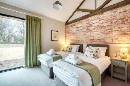 two beds in a room with a brick wall at Downs in Blewbury