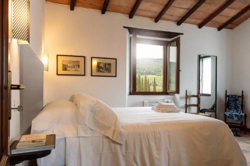 a bedroom with a white bed with a window at Tenuta Il Cicalino in Massa Marittima