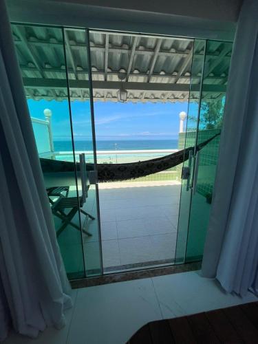 a room with a view of the beach through a glass window at Hotel Aconchego Da Vila in Saquarema