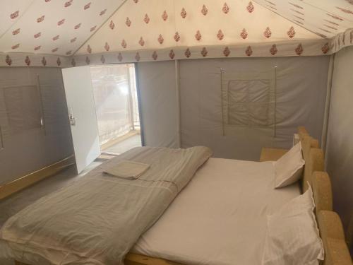 a bed in a room with a tent at Jaisalmer Safari Base & Camp in Khuri