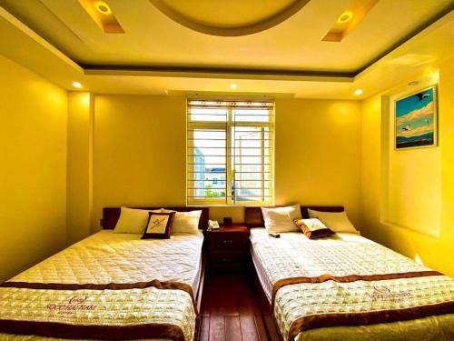 two beds in a room with yellow walls and a window at Ngọc Hải Nam Hotel - Khách Sạn Nhơn Trạch in Nhơn Trạch