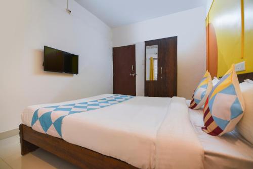 a bedroom with a large bed with a tv on the wall at Super OYO 77994 The G Stay in Chinchiwad