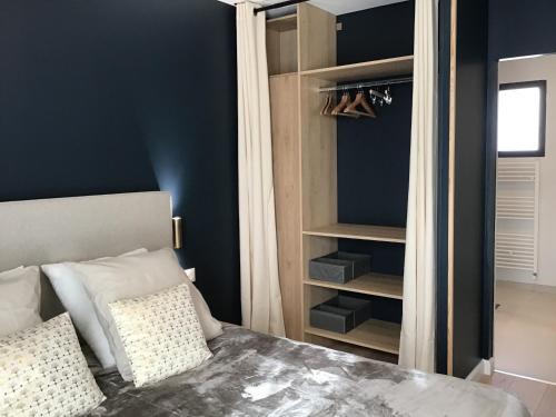 a bedroom with blue walls and a bed with pillows at Au Coeur d'Omaha Beach - Colleville-sur-Mer - Gîte 1 in Colleville-sur-Mer