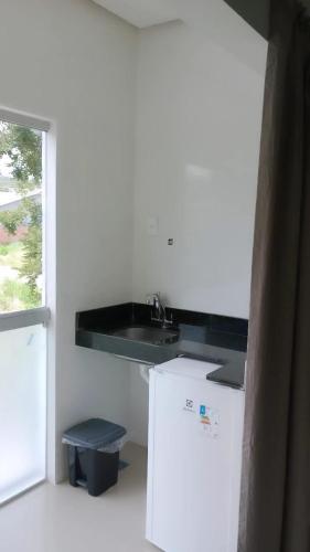 a kitchen with a sink and a white refrigerator at Pousada Trilha do Sol in Pirenópolis