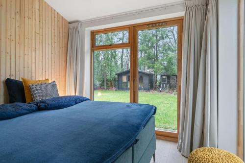 a bedroom with a blue bed and a large window at Nieuwe luxe villa in het bos in Zorgvlied