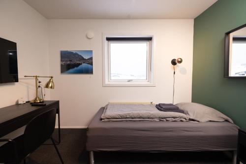 a bedroom with a bed and a desk and a window at Kulukis Downtown Hostel in Nuuk