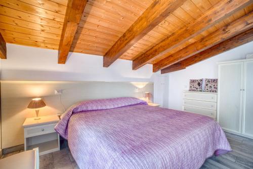 a bedroom with a purple bed and wooden ceilings at Casavacanzelemore - Casa Zoe in Valfabbrica