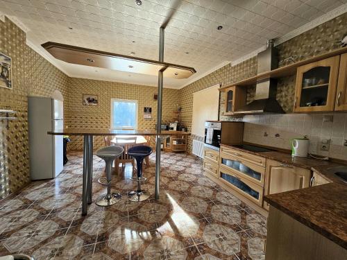 a large kitchen with a counter and stools in it at Šubrakkrasti in Vestiena