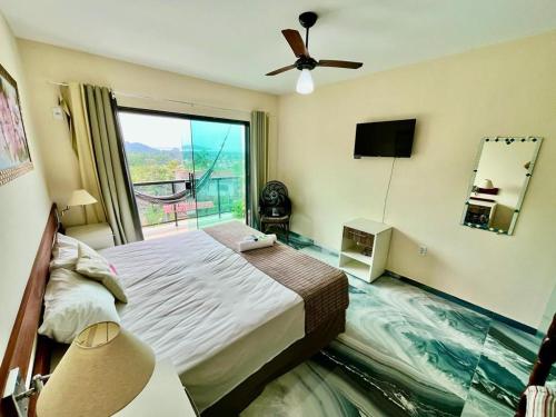 a bedroom with a bed and a large window at POUSADA OHANA PARATY in Paraty