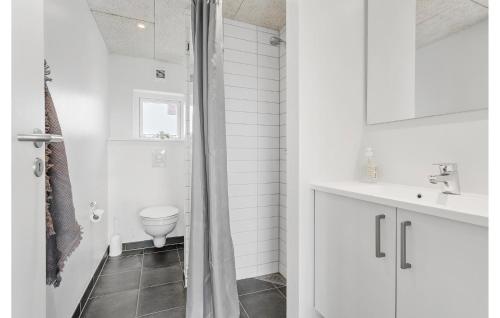 uma casa de banho branca com um chuveiro e um WC. em Amazing Home In Ringkbing With Kitchen em Søndervig