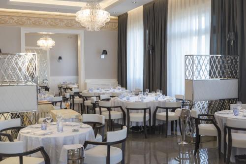 a dining room with white tables and chairs and a chandelier at Hotel Grande Italia in Chioggia