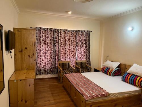 a bedroom with two beds and a window with a curtain at The Puma house in Leh