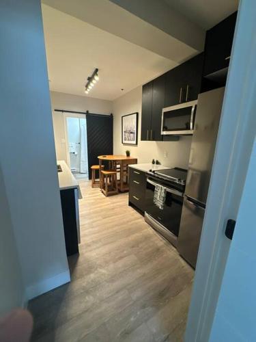 a kitchen with black cabinets and a kitchen with a table at Modern One Bedroom Suite in Halifax