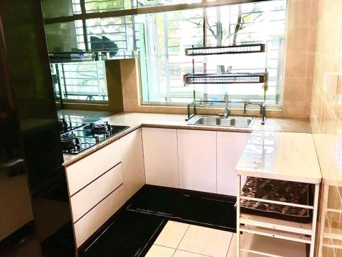 a white kitchen with a sink and a window at Eden Height Cozy & Spacious Condominiums in City of Kuching in Kuching
