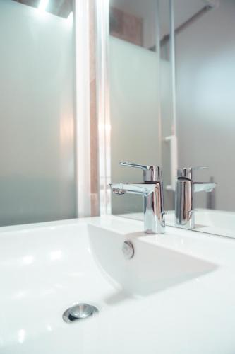 un lavabo de salle de bain avec deux robinets et un miroir dans l'établissement Le Nœud du Diable - T3 spacieux, à Tours