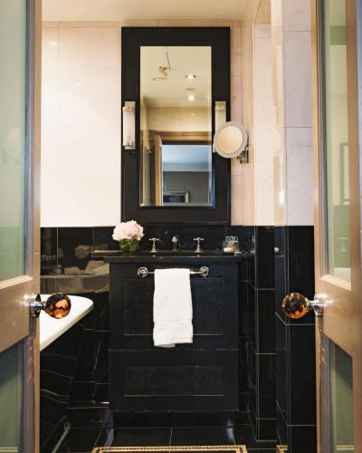 a black bathroom with a sink and a mirror at Althoff St James's Hotel & Club London in London