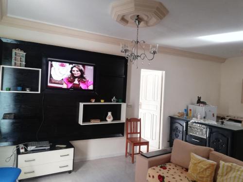 uma sala de estar com televisão numa parede preta em Darna em El Haouaria