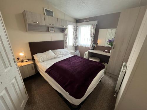 a bedroom with a large bed with a purple blanket at Heron, Sea View, Scratby - California Cliffs, Parkdean, sleeps 6, bed linen and towels included, pet free, onsite entertainment available in Scratby
