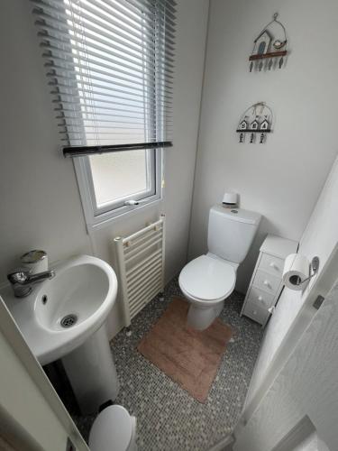 a white bathroom with a toilet and a sink at Heron, Sea View, Scratby - California Cliffs, Parkdean, sleeps 6, bed linen and towels included, pet free, onsite entertainment available in Scratby