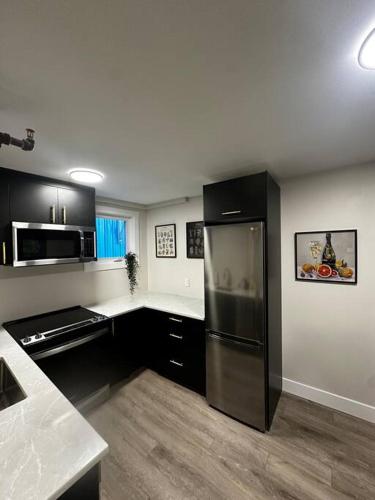 a kitchen with black cabinets and a stainless steel refrigerator at Quaint Queen Suite Central HFX in Halifax